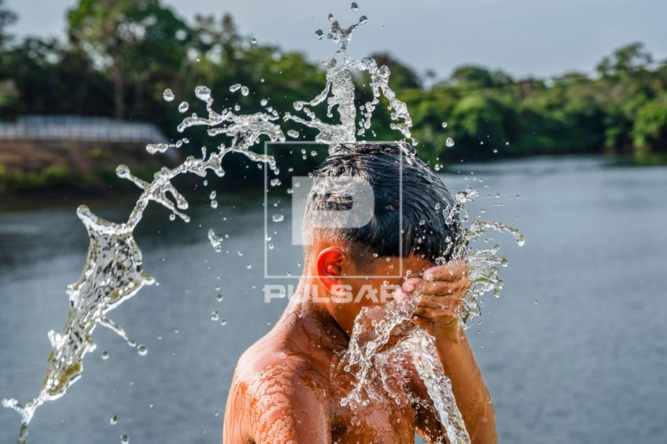 Menino se banha com mangueira - ao fundo Rio Manaquiri 