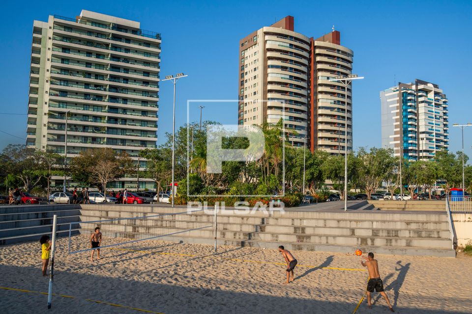 Pessoas jogando vôlei de areia na Praia da Ponta Negra - edifícios ao fundo