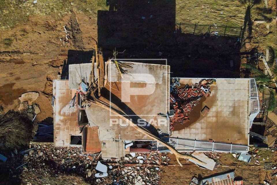 Vista de drone de moradia destruída com tronco de árvore no teto após a enchente no Vale do Taquari