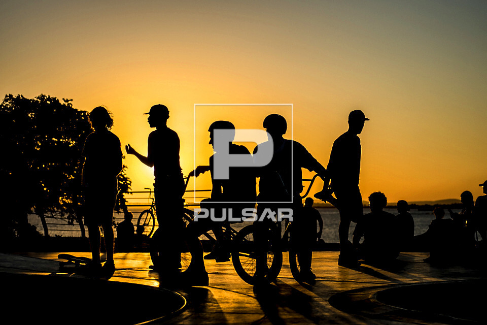 Jovens em pista de skate com o pôr do sol na orla do Rio Guaíba - 
