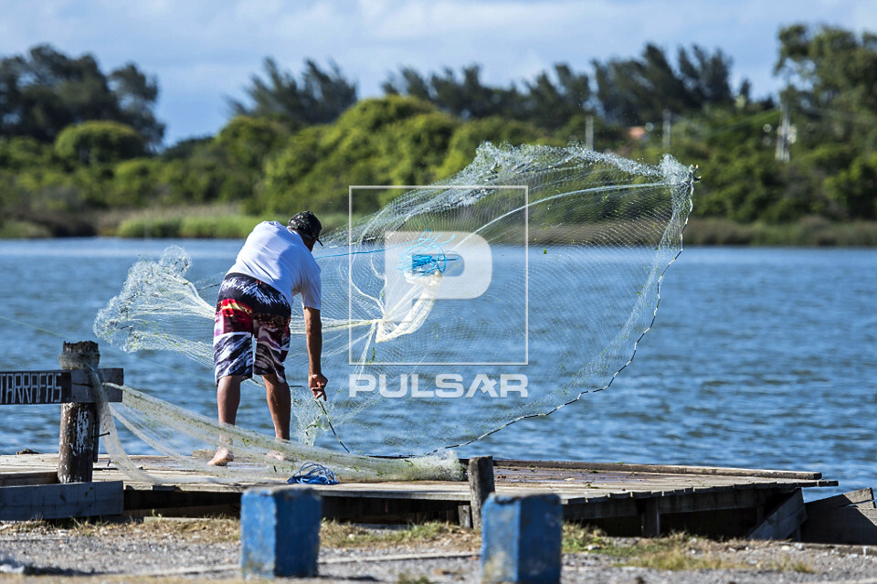 Pescador jogando tarrafa no estuário do rio Tramandaí