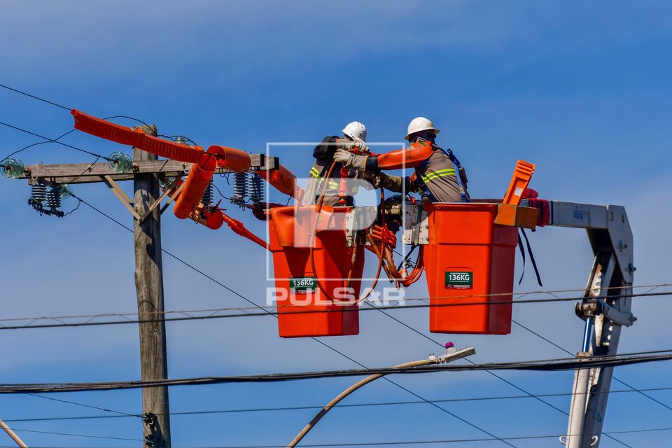 Trabalhadores fazendo reparo de rede elétrica após estragos causados por fortes ventos