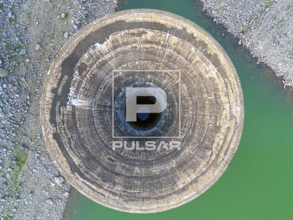 Vista de drone do vertedouro tulipa da barragem de Caconde com reservatório em nível baixo em período de es