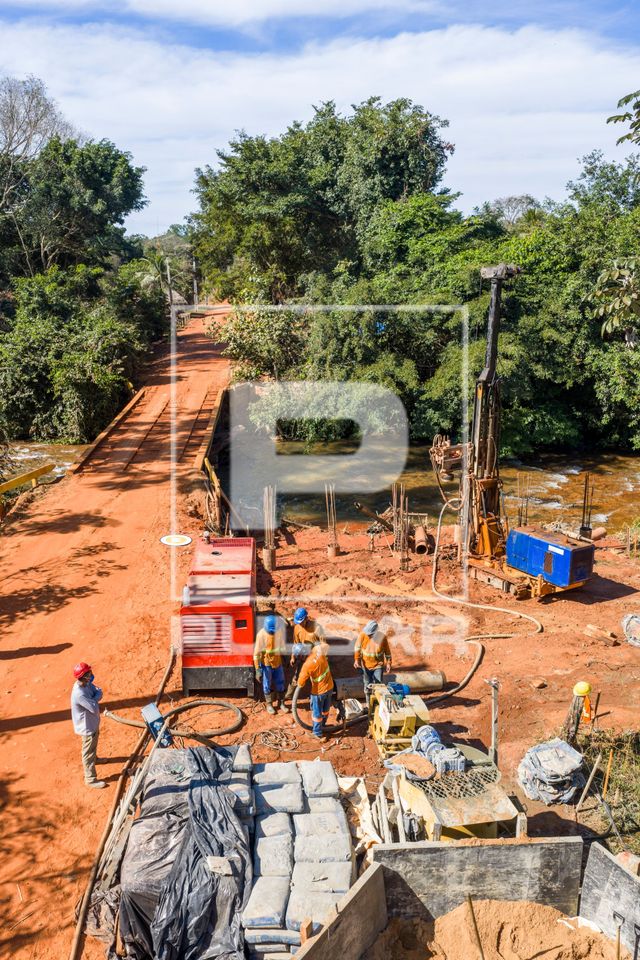 Vista de drone de trabalhadores na obra de construção da ponte de concreto na Comunidade Cachoeira Rica - MR
