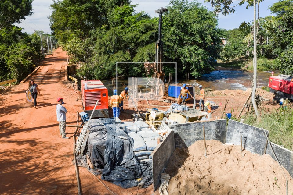 Vista de drone de trabalhadores na obra de construção da ponte de concreto na Comunidade Cachoeira Rica - MR