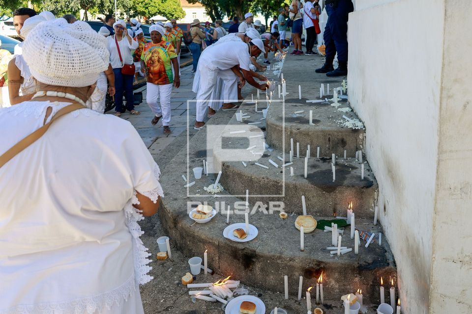 Fiéis de religiões de matriz africana fazendo oferendas durante peregrinação por cinco igrejas na celebra�