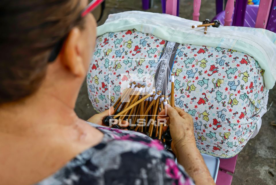 Rendeira produzindo renda de bilro