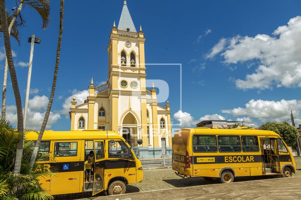 Micro-ônibus de transporte escolar estacionados em frente à Igreja Matriz do Divino Espírito Santo
