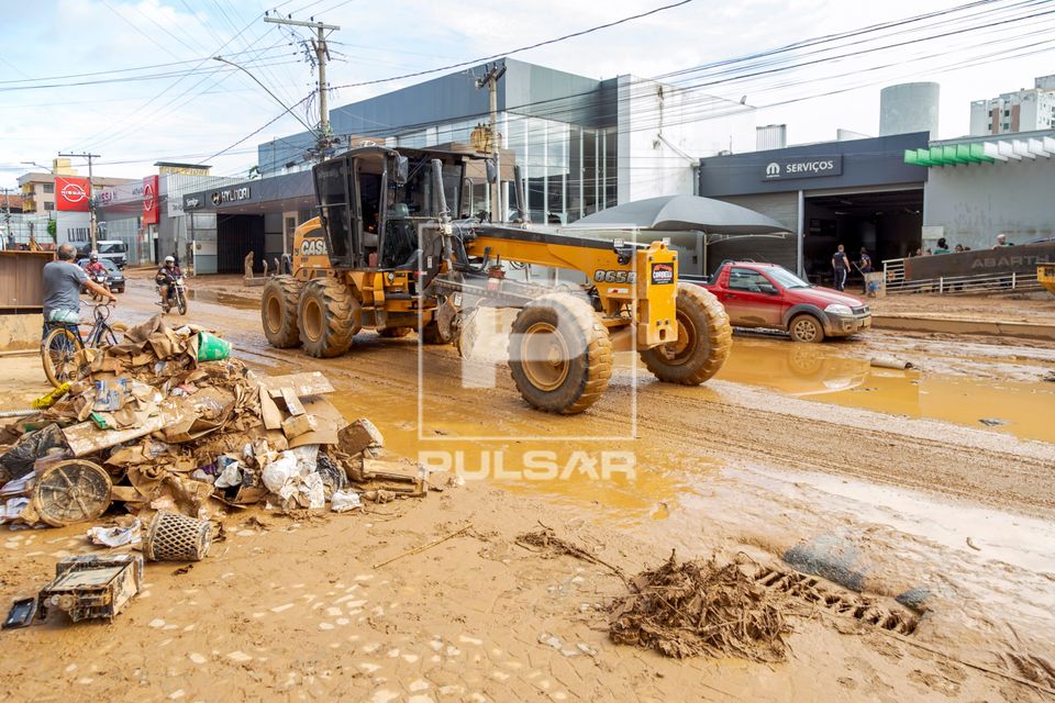 Motoniveladora fazendo limpeza da lama na Avenida Beira Rio após enchente do Rio Ubá causada por fortes chuv
