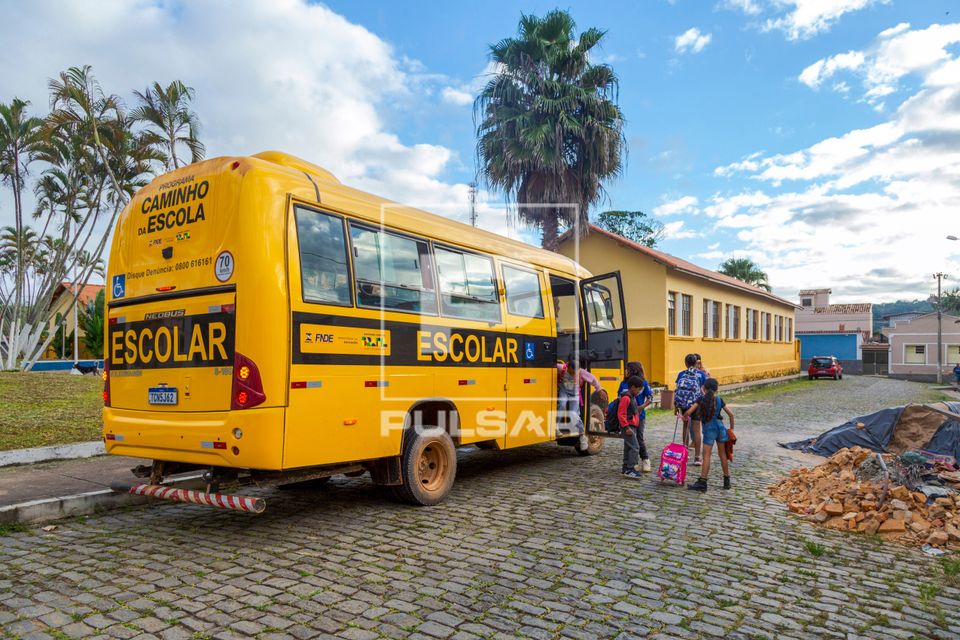 Alunos desembarcando de micro-ônibus de transporte escolar em frente à Escola Municipal Francisco Peixoto  