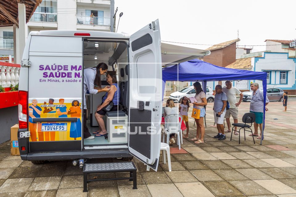 Enfermeira aplicando vacina em mulher durante campanha contra covid-19 e gripe dentro do vacimóvel na Praça 