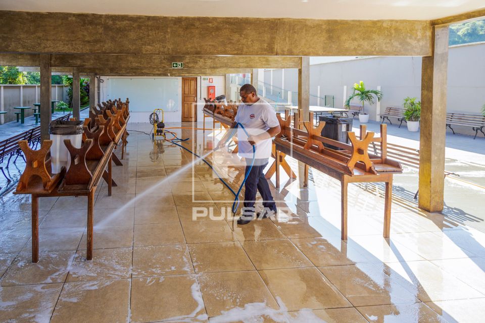 Funcionário lavando piso da área da cantina da escola 