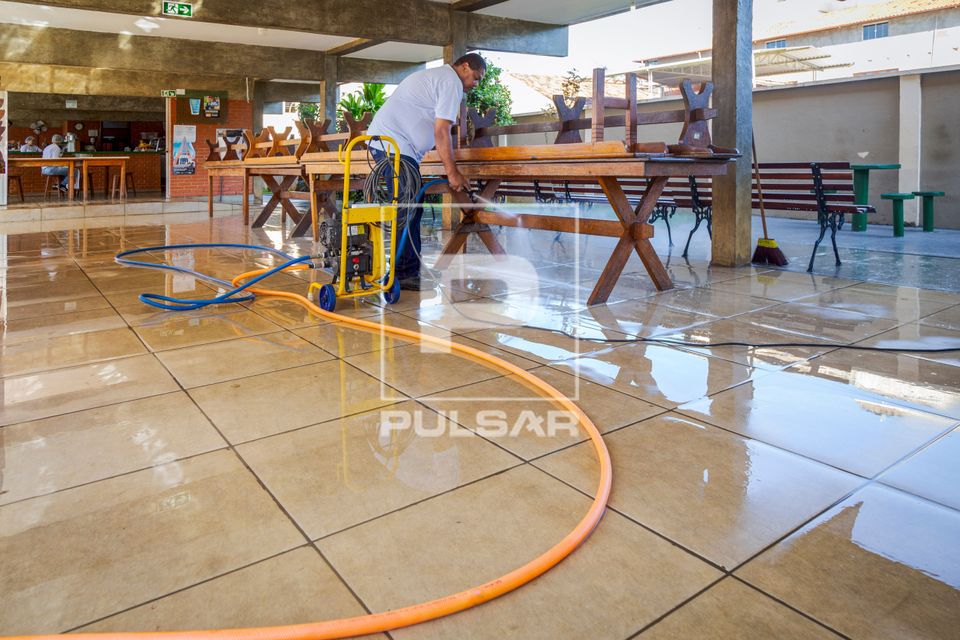Funcionário lavando piso da área da cantina da escola 