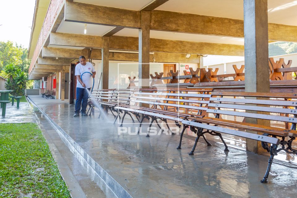 Funcionário lavando piso da área da cantina da escola 
