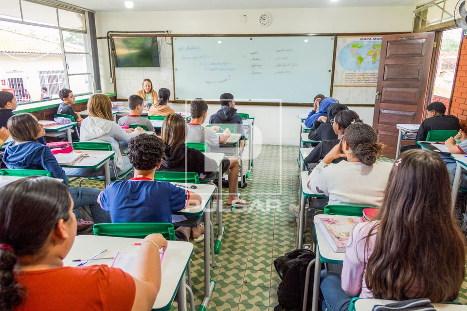 Professora fazendo chamada de presença de alunos em sala de aula