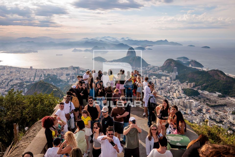 Turistas no Cristo Redentor , Baía da Guanabara ao fundo e Complexo do Pão de Açúcar à direita