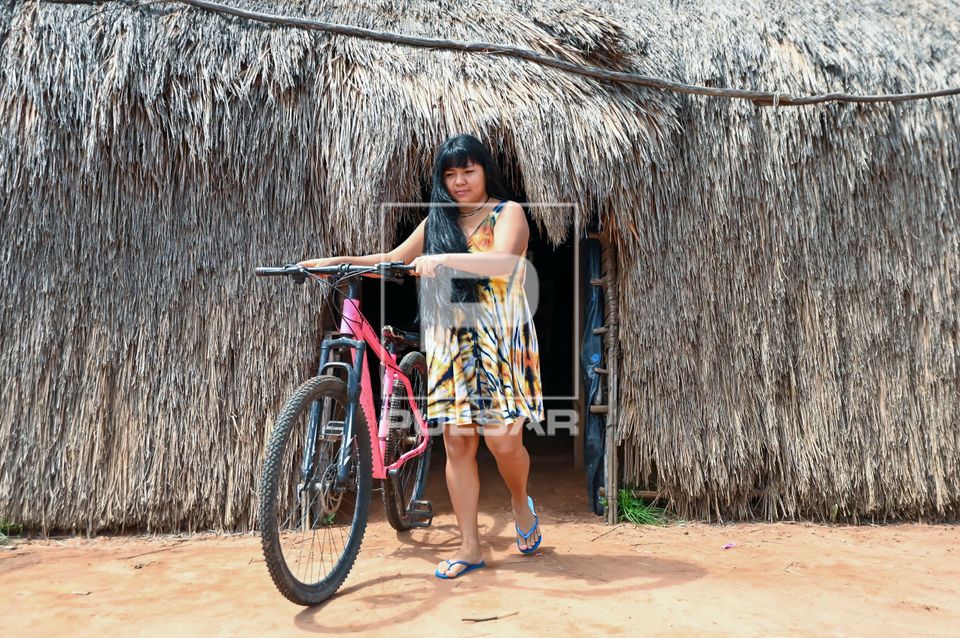 Indígena da etnia Wauja saindo da oca com bicicleta - Parque Indígena do Xingu
