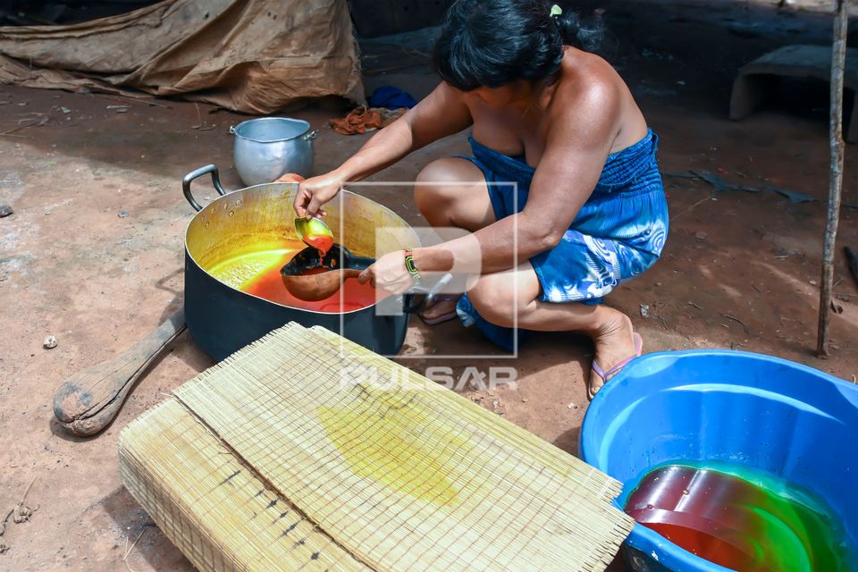 Indígena Wauja separando óleo da massa de pequi derretido na caldeirão e colocando para coar - Parque Indí