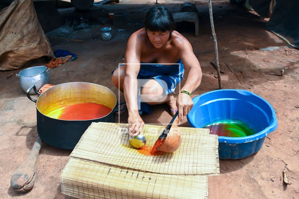 Indígena Wauja separando óleo da massa de pequi derretido na caldeirão e colocando para coar - Parque Indí