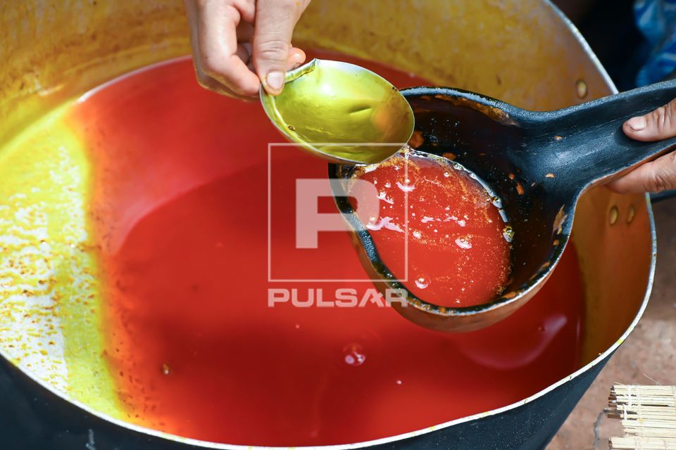 Indígena Wauja separando óleo da massa de pequi derretido na caldeirão e colocando para coar - Parque Indí