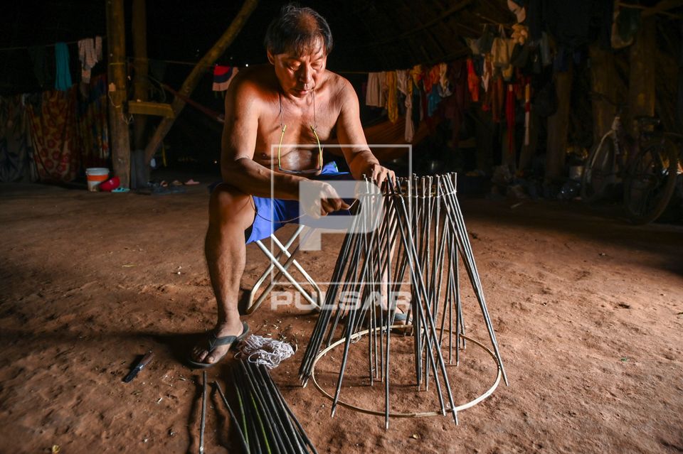Indígena Wauja amarrando varetas para confecção de armadilha de peixes kuluto ou matapi em forma de cone - 