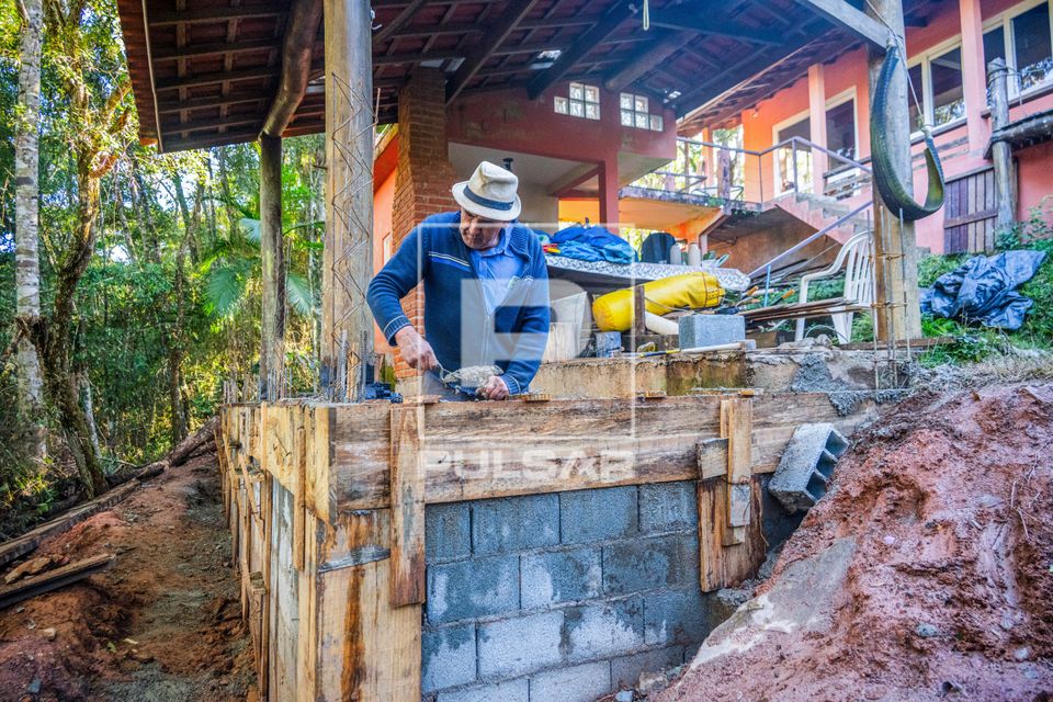Pedreiro usando pá de pedreiro para completar concreto na forma de madeira ou caixaria durante obra residenci