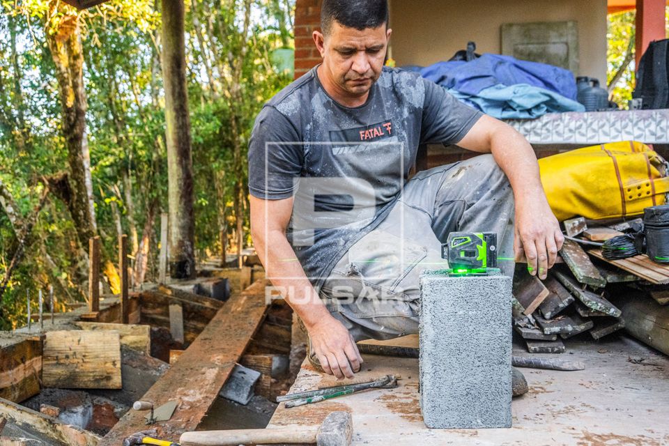 Pedreiro armando nível a laser verde para perfeito alinhamento e nivelamento das paredes de obra residencial