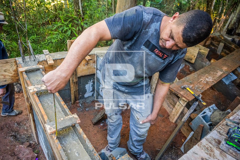 Pedreiro usando trena para perfeito alinhamento e nivelamento das paredes de obra residencial