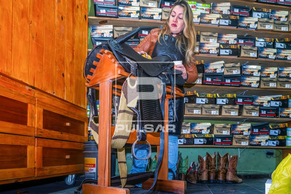 Seleira e sapateira encerando couro de sela de cavalo