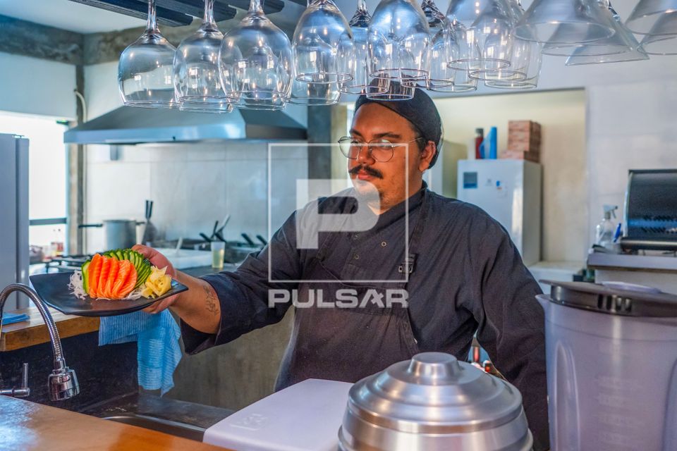Chef de cozinha e proprietário de restaurante de comida japonesa entregando prato de Sashimi