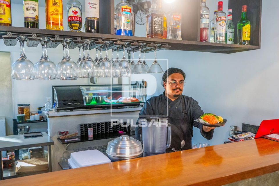 Chef de cozinha e proprietário de restaurante de comida japonesa entregando prato de Sashimi