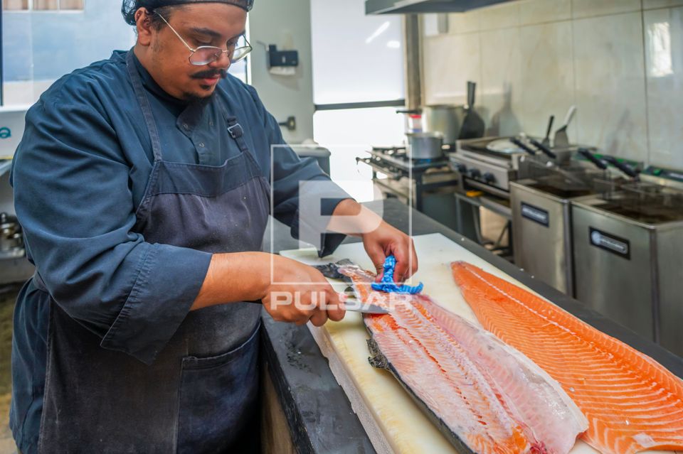 Chef de cozinha e proprietário de restaurante de comida japonesa retirando espinha de peixe Salmão