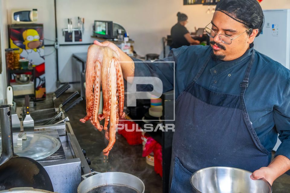 Chef de cozinha e proprietário de restaurante de comida japonesa colocando o Polvo para cozinhar