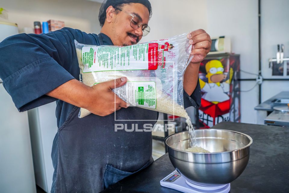 Chef de cozinha e proprietário de restaurante de comida japonesa pesando porção de arroz para sushi
