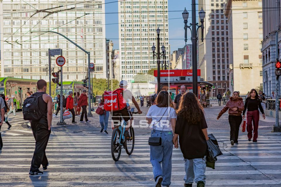 Ciclista entregador de comida por aplicativo e pessoas atravessando na Rua Xavier de Toledo com Praça Ramos d