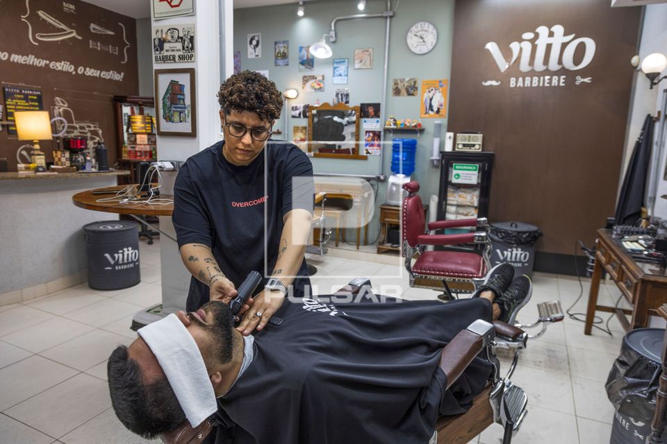 Barbeira fazendo a barba de cliente em barbearia no bairro de Perdizes 