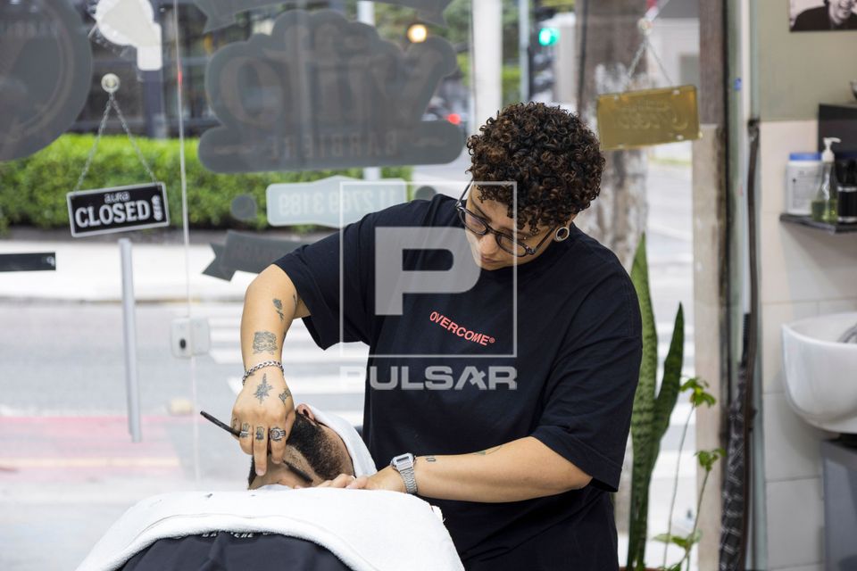 Barbeira fazendo a barba de cliente em barbearia no bairro de Perdizes 