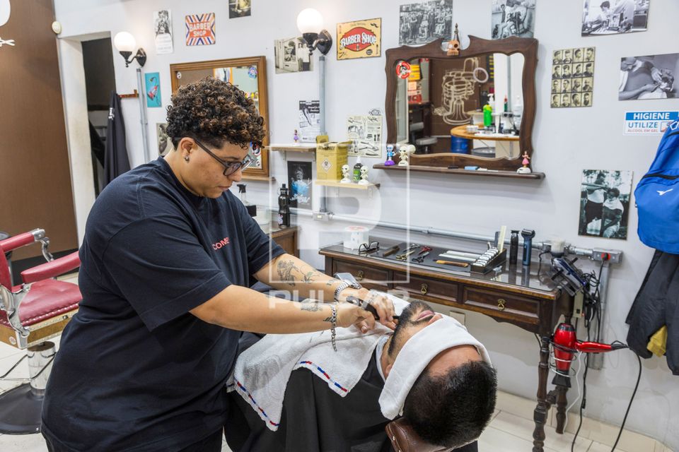 Barbeira fazendo a barba de cliente em barbearia no bairro de Perdizes 