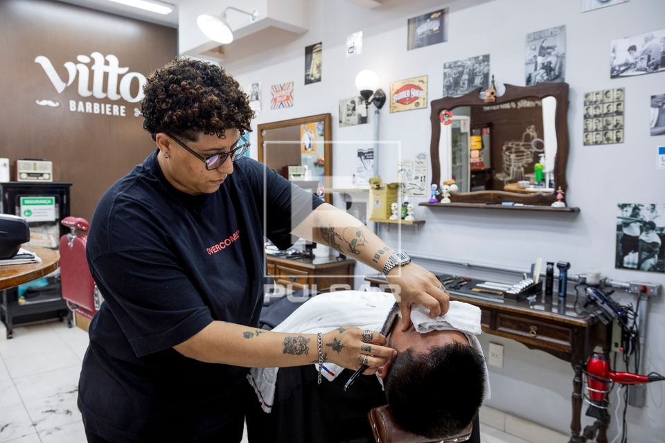 Barbeira fazendo a barba de cliente em barbearia no bairro de Perdizes 