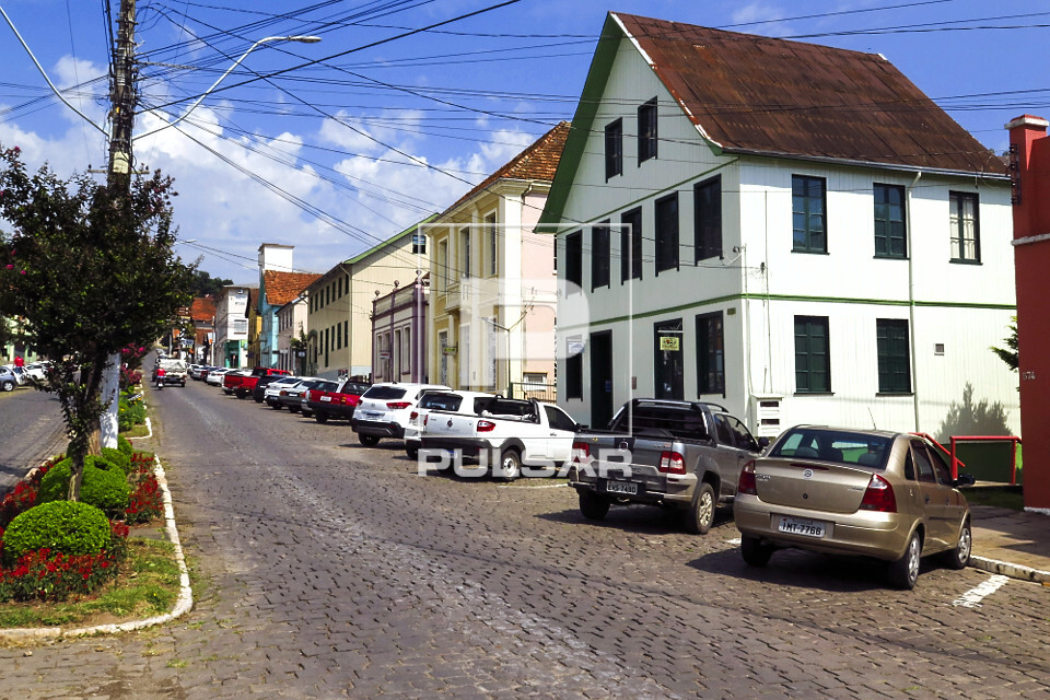 Casas com arquitetura típica italiana e veículos estacionados em rua com alive no centro da cidade - 