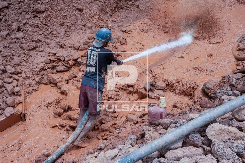 Trabalhador esguichando água no morro em garimpo de ouro legal no distrito Lourenço