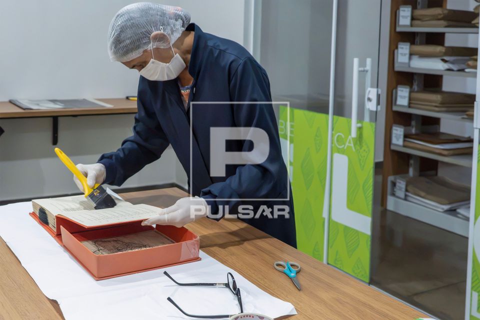 Trabalhadora do Setor de Obras Raras da Biblioteca Pública Estadual Elcy Lacerda fazendo limpeza em livro