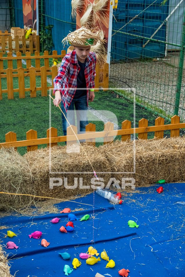 Menino de 10 anos brincando na pescaria de uma festa junina
