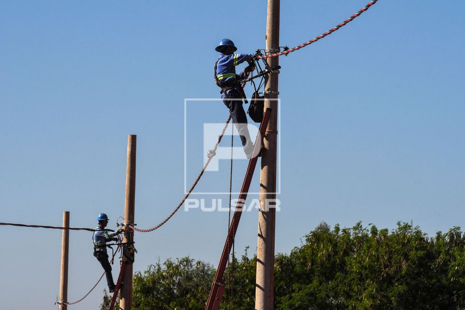Trabalhadores instalando rede elétrica em novo bairro residencial