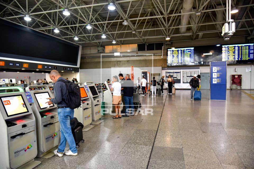 Pessoas utilizando máquinas de autoatendimento para check-in no saguão do RIOgaleão - Aeroporto Internacion