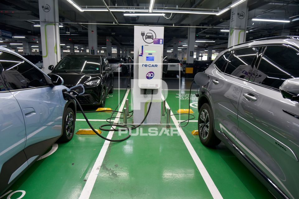 Carros elétricos recarregando suas baterias em vagas exclusivas no estacionamento de supermercado