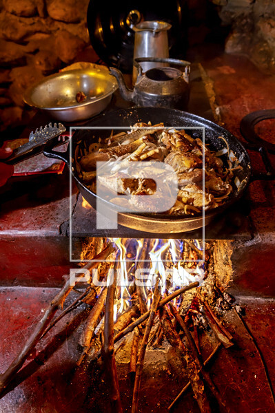 Frango caipira sendo preparado em forno a lenha
