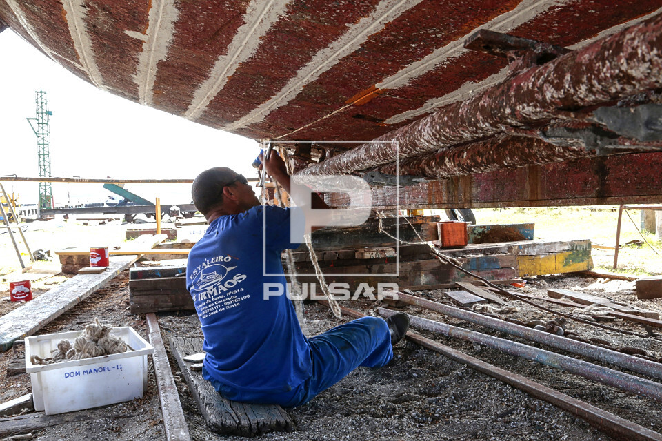 Trabalhador consertando barco em estaleiro - 