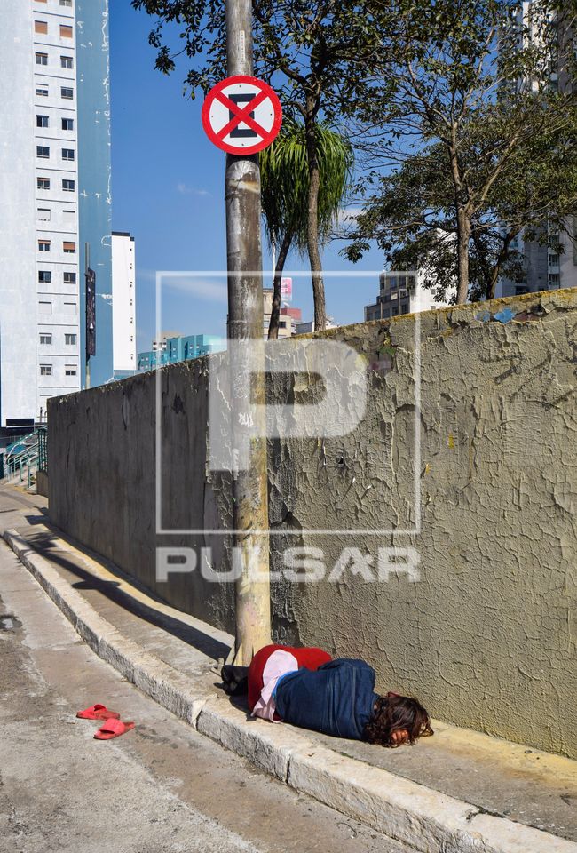 Pessoa em situação de rua dormindo na calçada