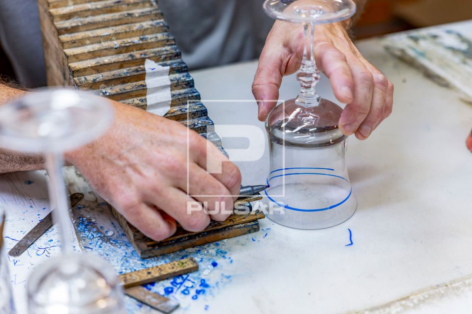 Artesão usa caneta hidrográfica na marcação do desenho de um copo de cristal para posterior lapidação de